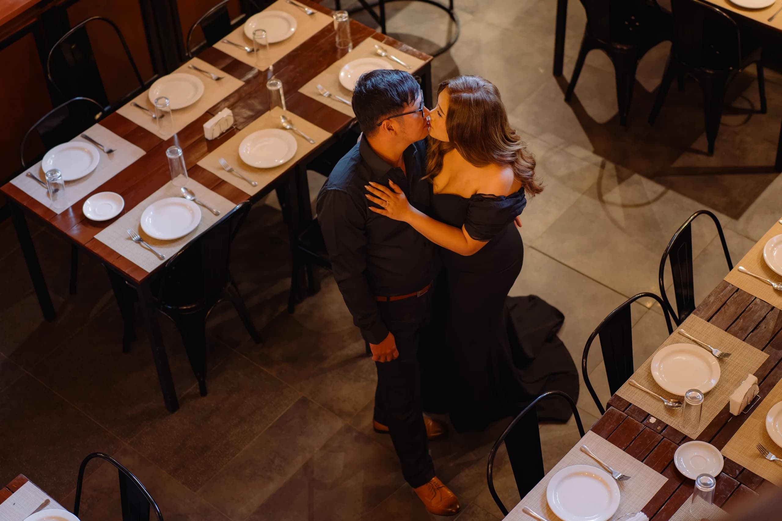 Ryan and Anne sharing a kiss, photographed from above in the café.