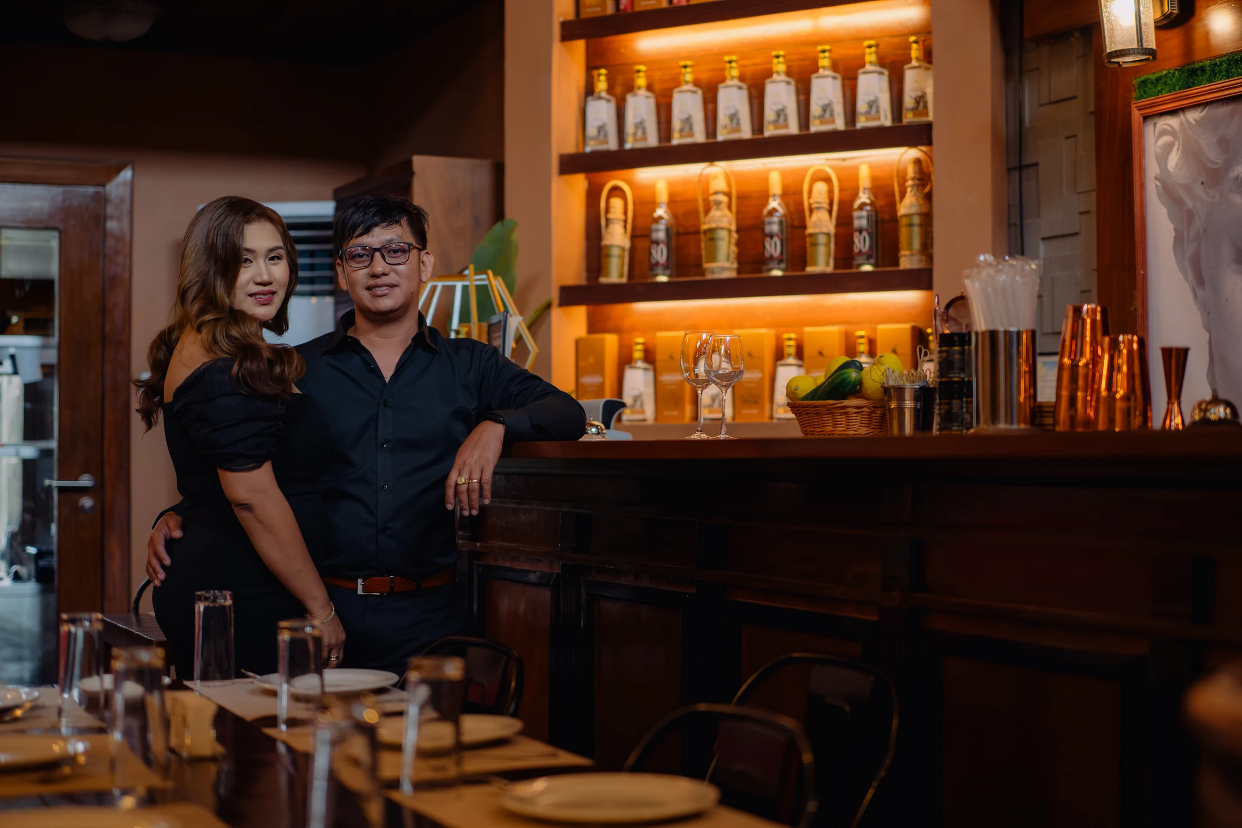 Ryan and Anne standing together beside the warmly lit bar.