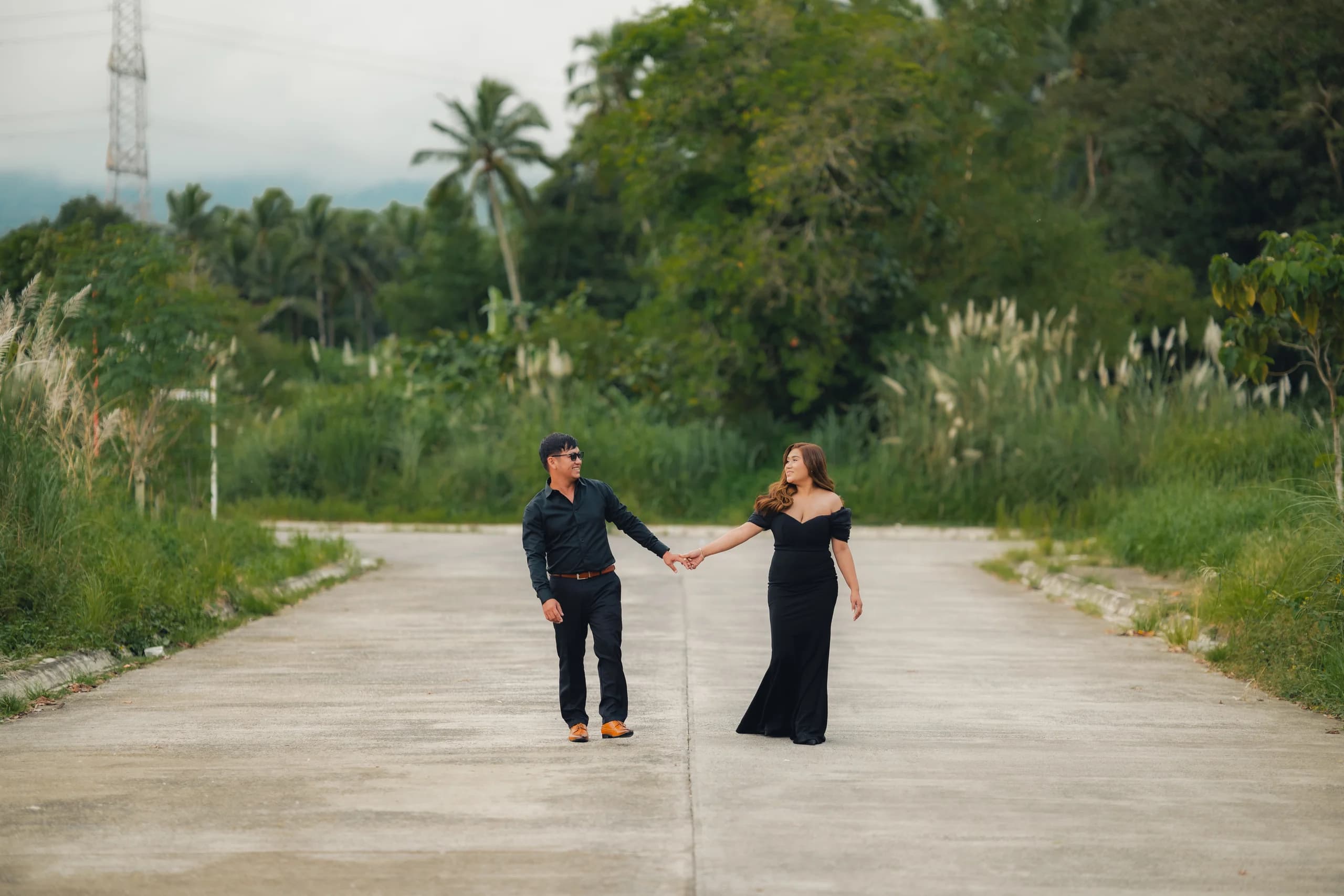 Ryan and Anne walking hand in hand along a quiet tree-lined road.